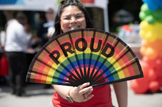Girl with rainbow fan that says proud