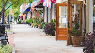 Charming sidewalk in Norcross downtown with planters, benches, and a welcoming shop entrance along a lively, walkable streetscape.