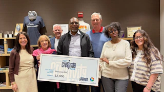 Seven people smiling indoors, holding a large check for $2,000 from Gwinnett Creativity Fund.